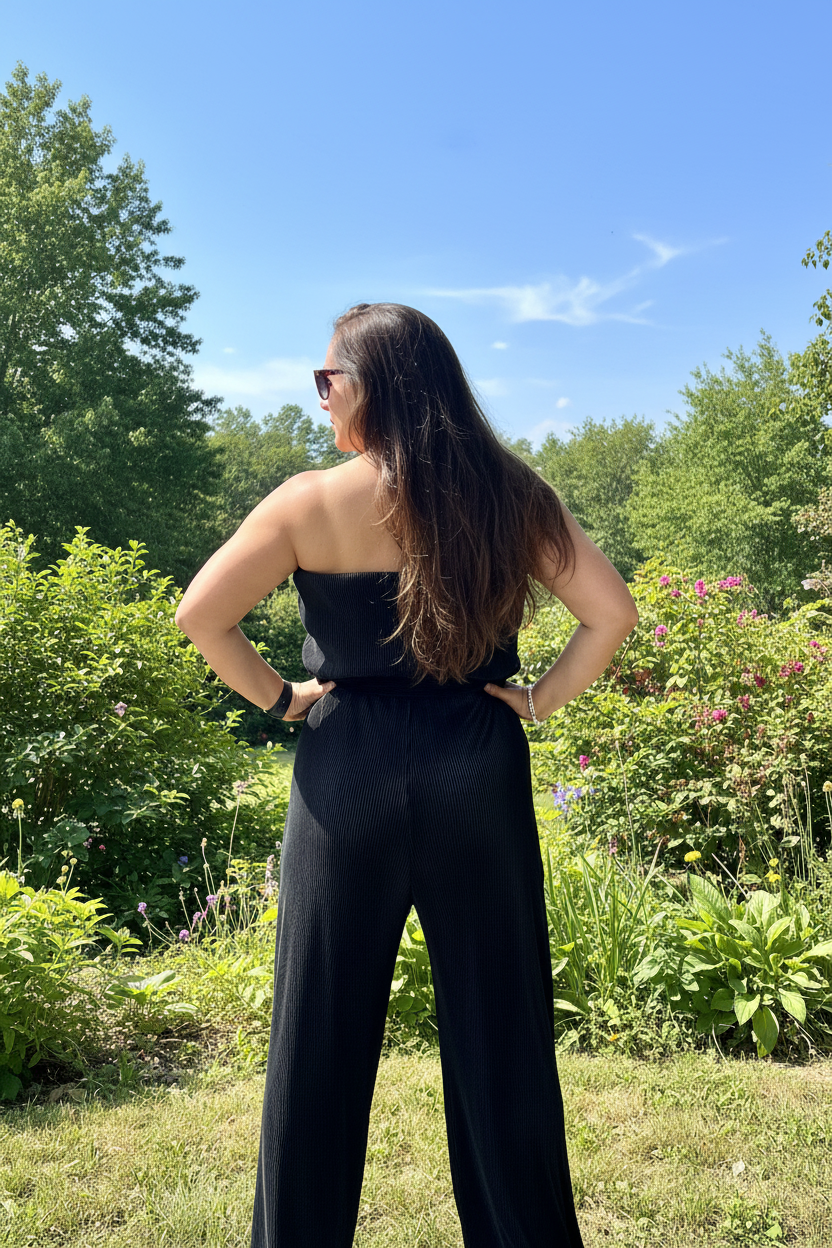 Chic black jumpsuit with plisse fabric, tube top style, and adjustable waist tie for versatile styling.