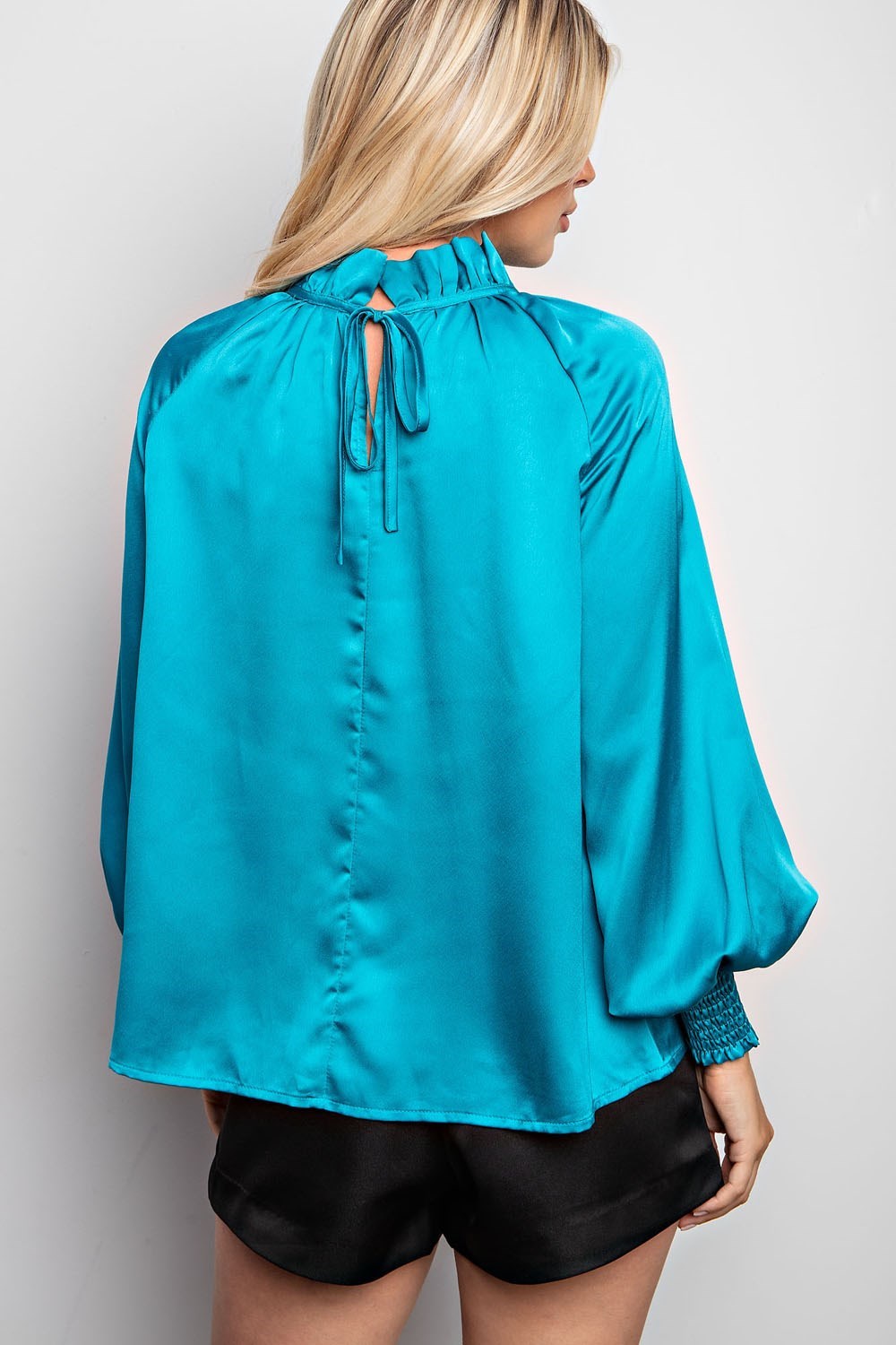 Teal blouse with feminine tie-back for versatile styling.